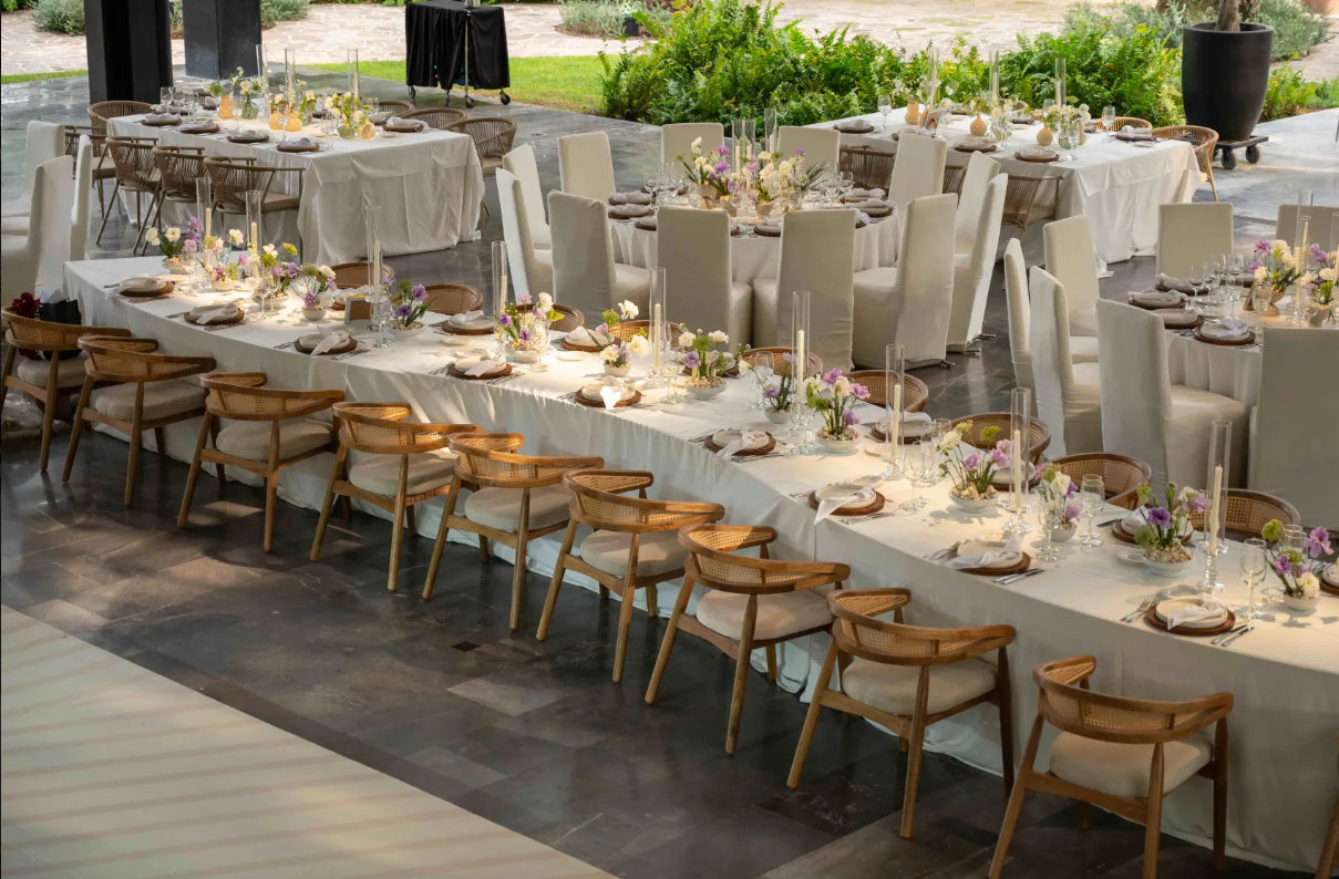 Mesa larga con sillas de madera Casa Sauce montada para un evento al aire libre